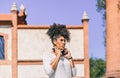 Young brunette girl with afro hair wearing black headphones walks pensively Royalty Free Stock Photo