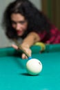 Young brunette girl aiming to ball playing billiard game