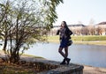 Young girl stands near river in city park on autumn day Royalty Free Stock Photo