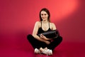 Young brunette girl in a black top crossing her legs. A sports woman on a red cherry background Royalty Free Stock Photo