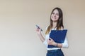 Young brunette girl with blue folder and pen on a light background Royalty Free Stock Photo