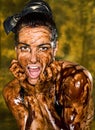 Young brunette girl on bright background covered chocolate cream all over her body and face, lifestyle people concept Royalty Free Stock Photo