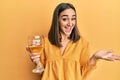 Young brunette girl drinking a glass of white wine celebrating achievement with happy smile and winner expression with raised hand Royalty Free Stock Photo