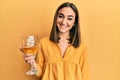 Young brunette girl drinking a glass of white wine looking positive and happy standing and smiling with a confident smile showing Royalty Free Stock Photo