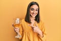 Young brunette girl drinking a glass of white wine smiling happy pointing with hand and finger Royalty Free Stock Photo