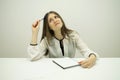 young brunette girl with flowing hair is sitting at a table with a notepad on the table