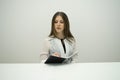 Young brunette girl with her hair straight sits at the table with a notebook in her hands Royalty Free Stock Photo