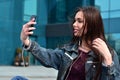 Young girl doing selfie on the background of an office building