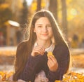 Young brunette girl in a purple sweater lies on fallen autumn leaves Royalty Free Stock Photo