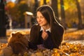 Young brunette girl in a purple sweater lies on fallen autumn leaves Royalty Free Stock Photo