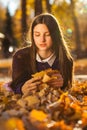 Young brunette girl in a purple sweater lies on fallen autumn leaves Royalty Free Stock Photo