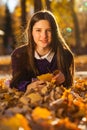 Young brunette girl in a purple sweater lies on fallen autumn leaves Royalty Free Stock Photo