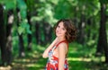 Young brunette girl in red dress posing on alley in summer park against trees Royalty Free Stock Photo