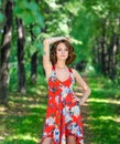 Young brunette girl in red dress posing on alley in summer park against trees Royalty Free Stock Photo