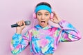 Young brunette girl singing song using microphone wearing sportswear afraid and shocked with surprise and amazed expression, fear Royalty Free Stock Photo