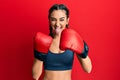 Young brunette girl using boxing gloves sticking tongue out happy with funny expression Royalty Free Stock Photo