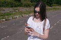 Young brunette girl walking in the stadium in a residential area and messaging on a mobile phone. Royalty Free Stock Photo