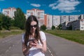 Young brunette girl walking in the stadium in a residential area and messaging on a mobile phone. Royalty Free Stock Photo