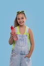 Young brunette girl wearing  denim overalls shorts stands with a phone and with a bottle of water Royalty Free Stock Photo