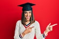 Young brunette girl wearing graduation cap smiling and looking at the camera pointing with two hands and fingers to the side Royalty Free Stock Photo