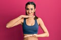 Young brunette girl wearing sportswear and braids gesturing with hands showing big and large size sign, measure symbol Royalty Free Stock Photo