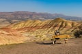 A young brunette with gray strands takes photographs with her smartphone sitting on a bench in Painted Hills Overlook