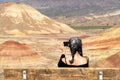 A young brunette with gray strands takes photographs with her smartphone sitting on a bench in Painted Hills Overlook