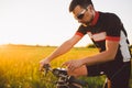 A young brunette guy on a mountain bike uses a cycling computer, a navigator in the field sunset of the day