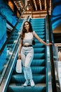 Young brunette Latina attractive woman with shopping bags on escalator in the fashion store mall. Royalty Free Stock Photo
