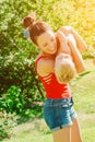 Young brunette mother lifting her son in park having fun enjoying motherhood.