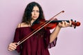 Young brunette musician woman with curly hair playing violin depressed and worry for distress, crying angry and afraid Royalty Free Stock Photo