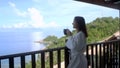Young brunette pretty woman in bathrobe in the mountain after spa treatment stands to the balcony drinks coffee enjoying Royalty Free Stock Photo