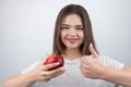 Young brunette seductive woman holding red apple in her hand showing like sign standing on isolated white background dietology and Royalty Free Stock Photo