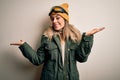 Young brunette skier woman wearing snow clothes and ski goggles over white background clueless and confused expression with arms