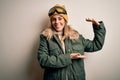 Young brunette skier woman wearing snow clothes and ski goggles over white background gesturing with hands showing big and large