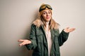 Young brunette skier woman wearing snow clothes and ski goggles over white background smiling cheerful with open arms as friendly