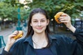 Young brunette with a smile holds two hamburgers in her hands