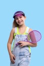 A young brunette smiling girl wearing  denim overalls shorts stands with a tennis racket in his hands Royalty Free Stock Photo