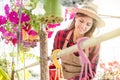 Young brunette smiling woman kindly treats flowers in a greenhouse. colorful and vibrant image