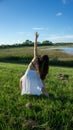 Young brunette spanish woman doing reverse warrior yoga pose in a field next to a lake with long curly hair Royalty Free Stock Photo