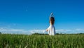 Young brunette spanish woman doing Vriksasana tree yoga pose in a field next to a lake with long curly hair Space in sky