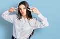 Young brunette teenager doing peace gesture close to eyes looking at the camera blowing a kiss being lovely and sexy Royalty Free Stock Photo