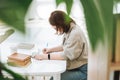 Young brunette teenager girl college student in glasses doing homework with mobile phone at modern library public place, green Royalty Free Stock Photo