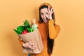 Young brunette teenager holding paper bag with groceries looking to side, relax profile pose with natural face and confident smile