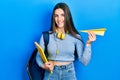 Young brunette teenager student holding books and paper plane smiling with a happy and cool smile on face Royalty Free Stock Photo