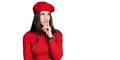 Young brunette teenager wearing french look with beret thinking concentrated about doubt with finger on chin and looking up Royalty Free Stock Photo