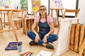 Young brunette woman at art studio sitting on the floor making fish face with lips, crazy and comical gesture