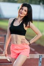 Portrait of young brunette woman athlete on stadium sporty lifestyle standing on track posing near the barriers running jumping to Royalty Free Stock Photo