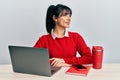 Young brunette woman with bangs working at the office with laptop looking to side, relax profile pose with natural face and Royalty Free Stock Photo