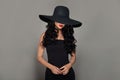 Young Brunette Woman in Black Cotton Dress and in black wide broad brim hat. Fashion Portrait of Brunette Hair Model Royalty Free Stock Photo